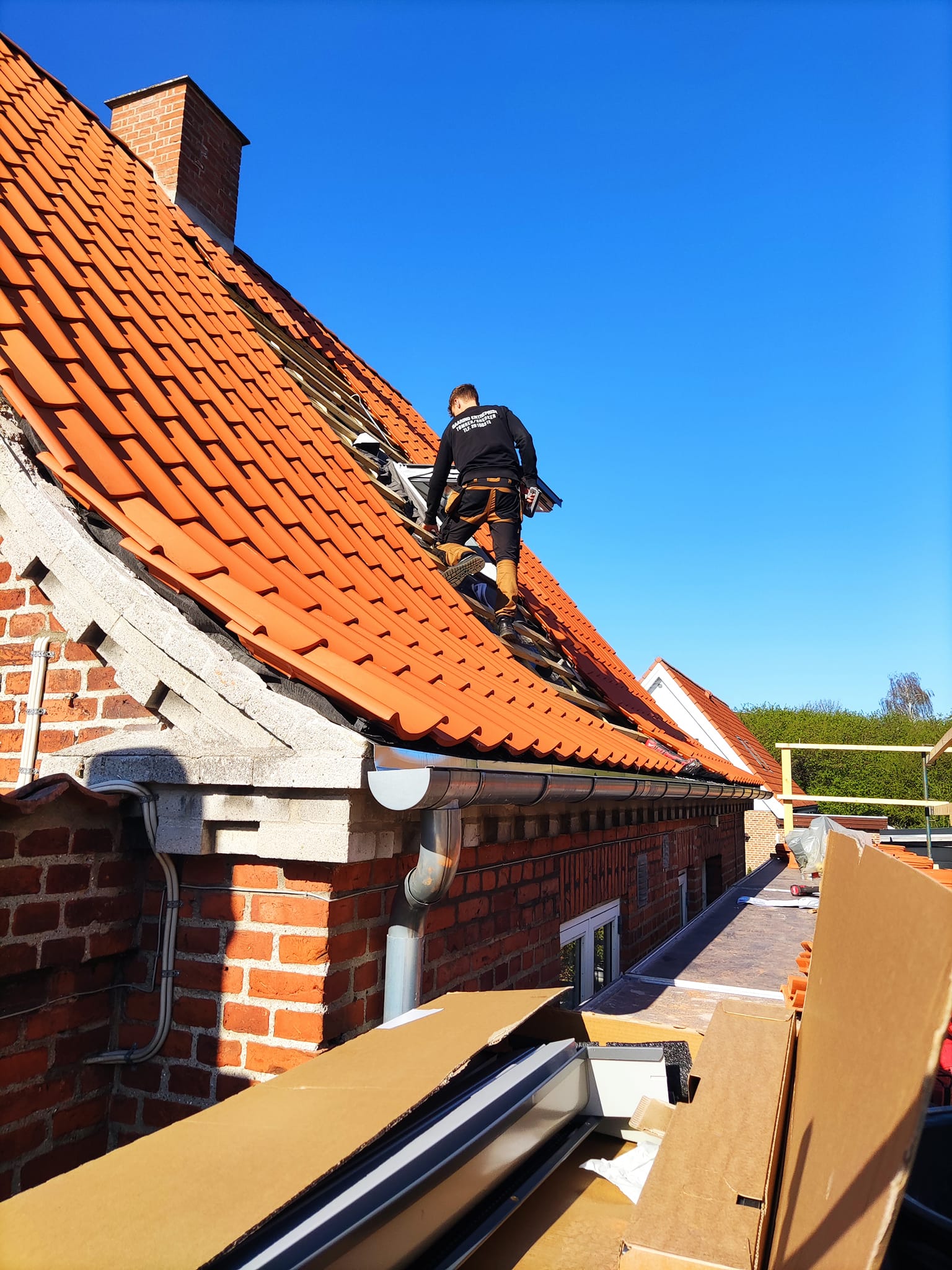 Murstensvilla med orange tegltag, tømrer fra Baaring Entreprise arbejder på nyt tag.